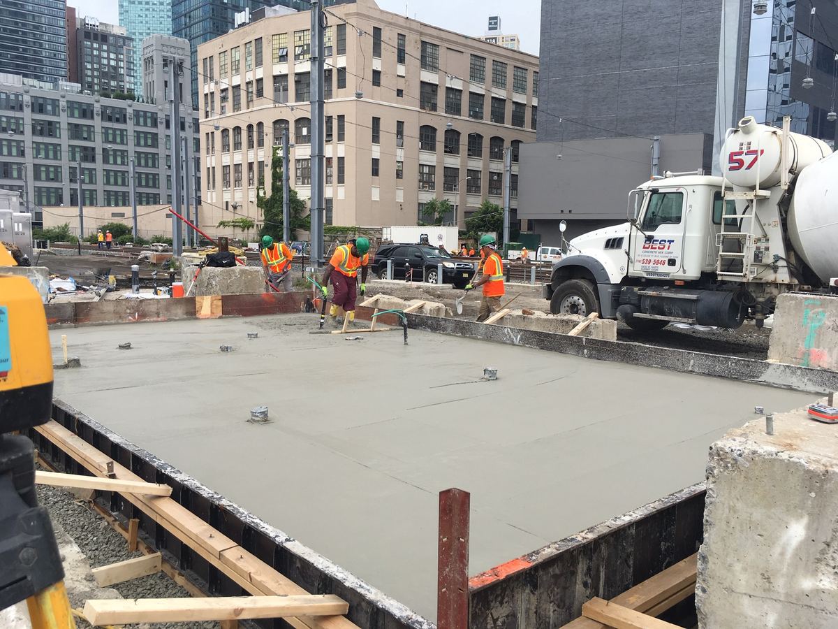 Finishing crew smoothing a large poured concrete foundation slab at a commercial job site