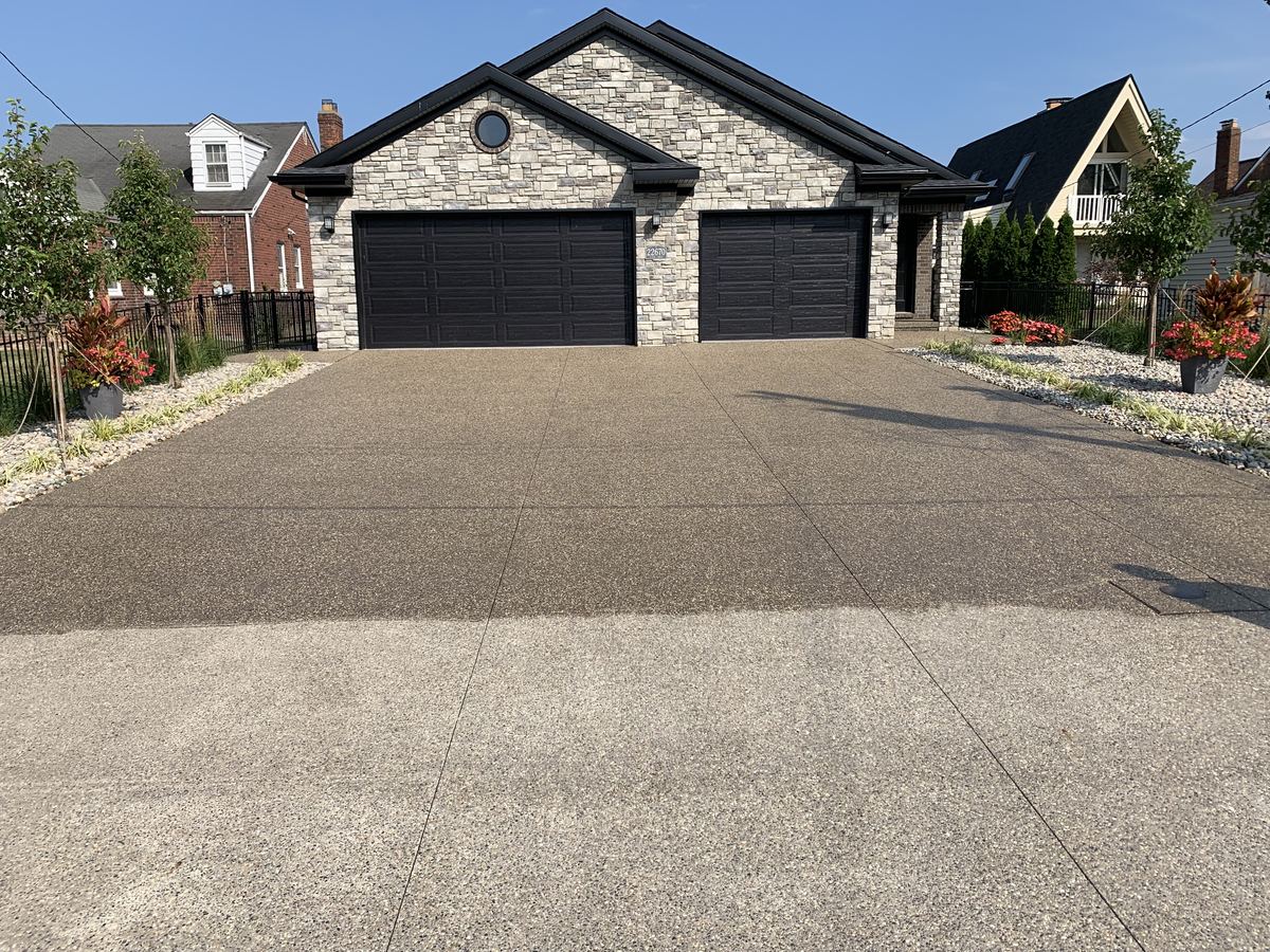 Finished exposed-aggregate concrete driveway in front of a home